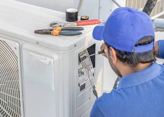 Technician checking an outdoor air conditioner with maintenance tools nearby